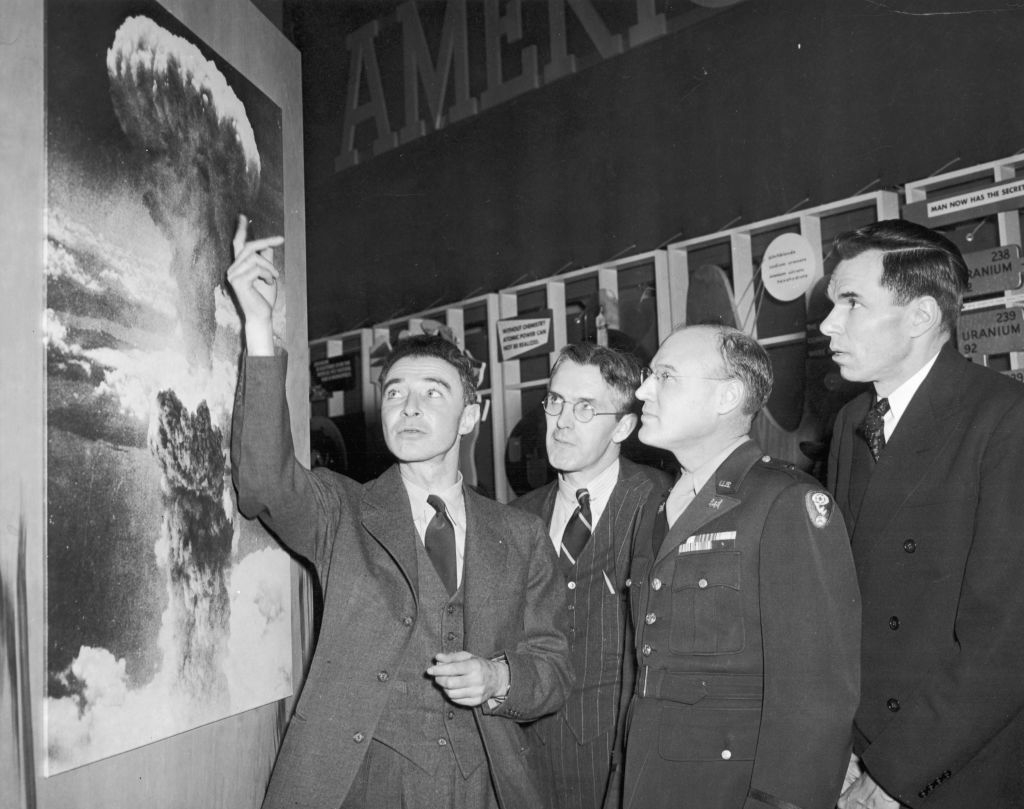 Four men in vintage attire examining a photo exhibit