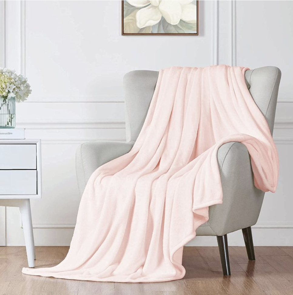 Soft pink throw blanket draped over a modern armchair in a stylish interior setting