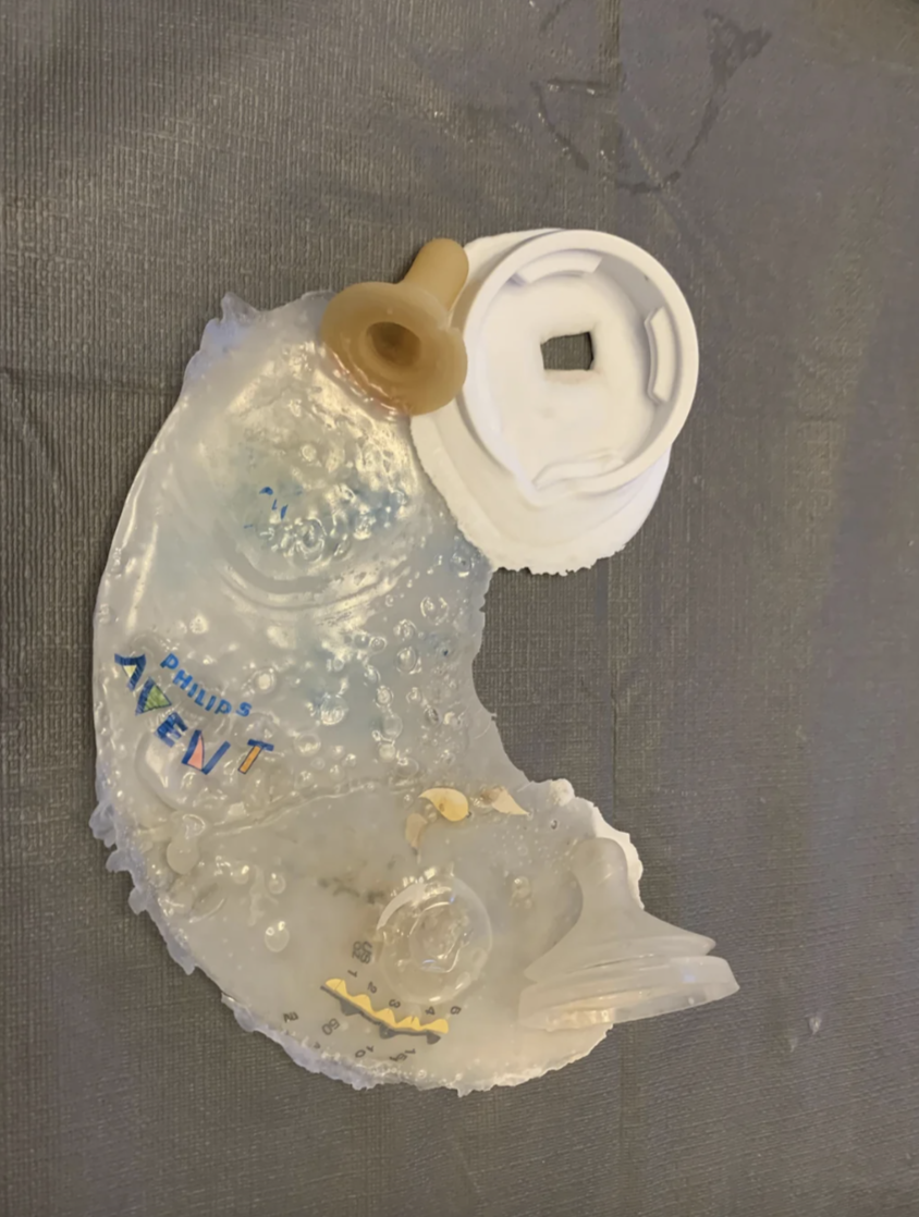 Melted baby bottle on a fabric surface, showcasing deformation from heat