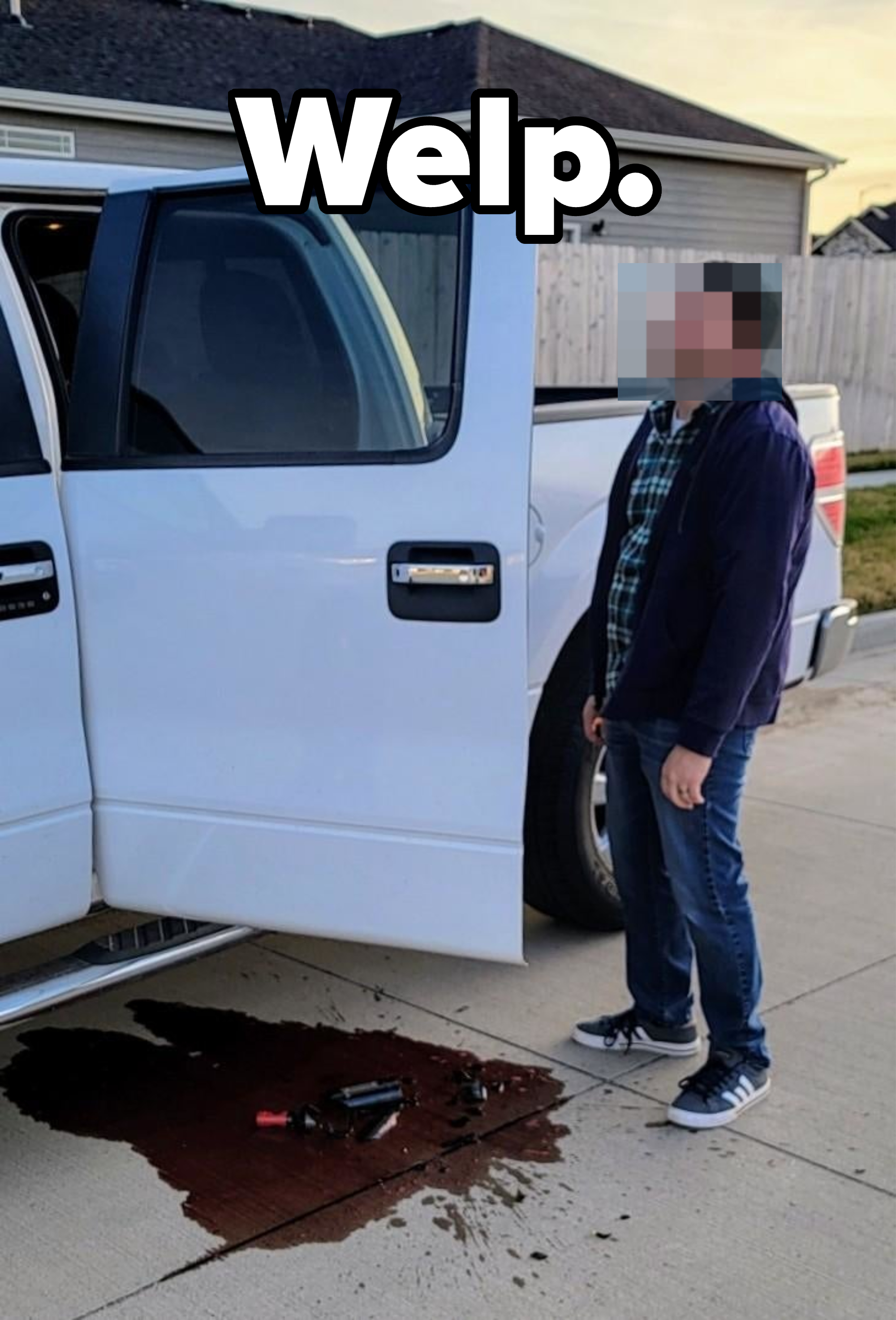 Man with a plaid shirt looking at a puddle under a white truck with the door open