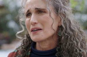 Close-up of an emotional woman with curly hair, expressing concern or sadness