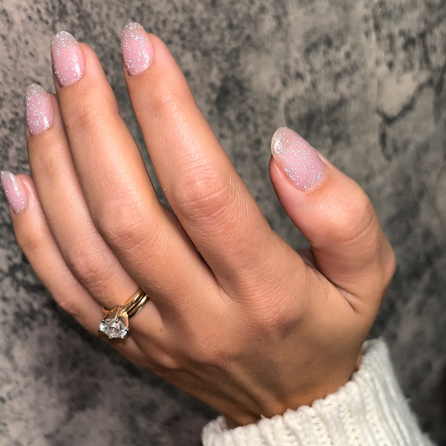 Hand displaying glittery manicure and a diamond ring