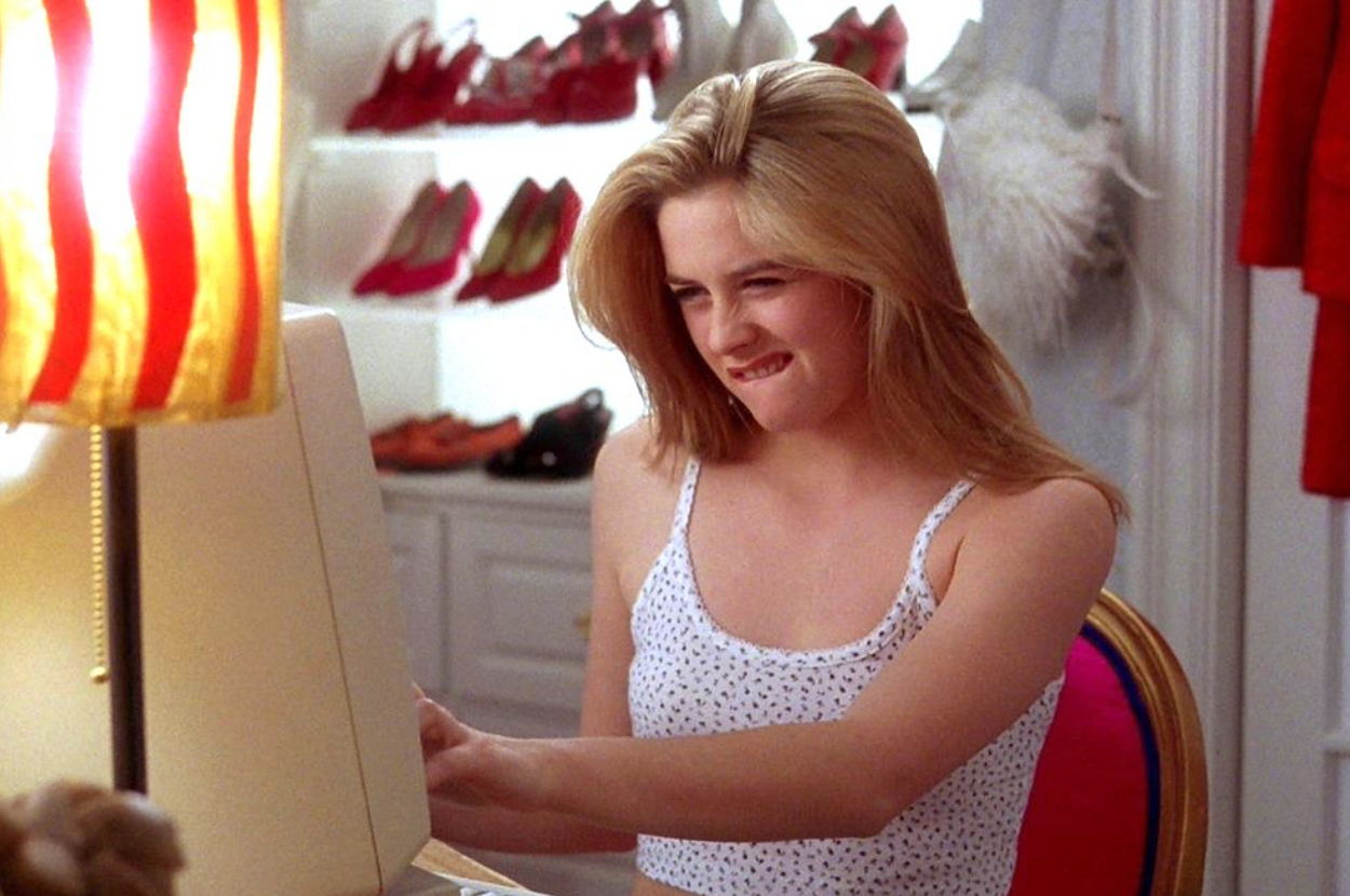 Cher Horowitz from Clueless sitting at a vanity, looks frustrated at a computer screen