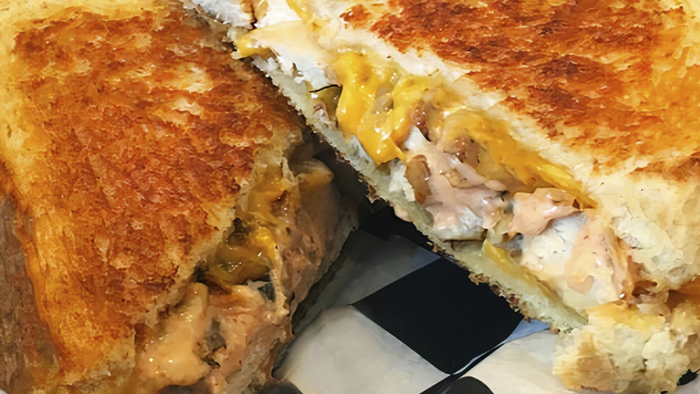 Grilled cheese sandwich cut in half, melted cheese visible, on a white plate