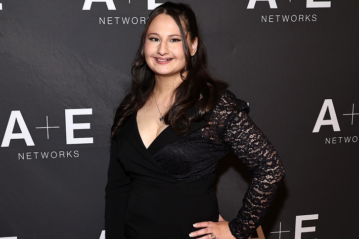 Woman in a black dress with lace sleeve posing at an A+E Networks event