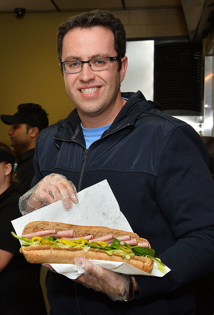 Jared Fogle holding a sandwich at a Subway shop, smiling at the camera