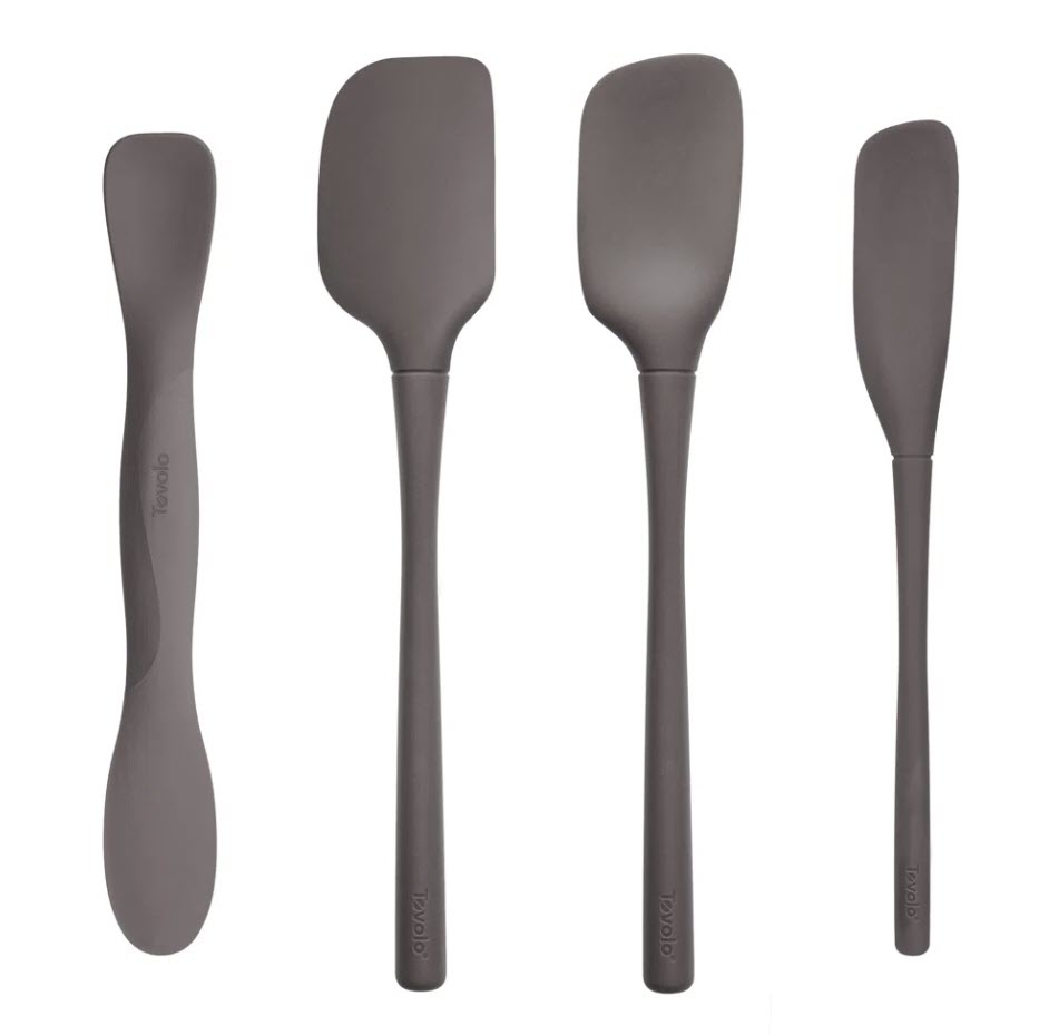 Four silicone kitchen utensils, including a spoonula, spatula, and two types of spreaders, arranged side by side