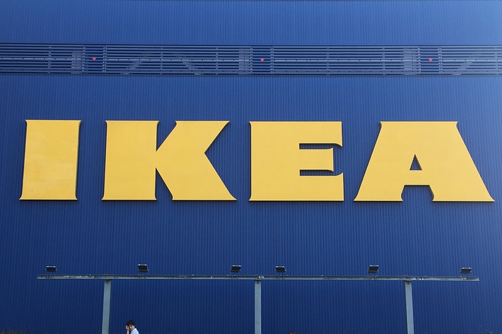 IKEAの店舗外壁に大きな黄色い文字で「IKEA」と表示されている、前を歩く人々がいる。
