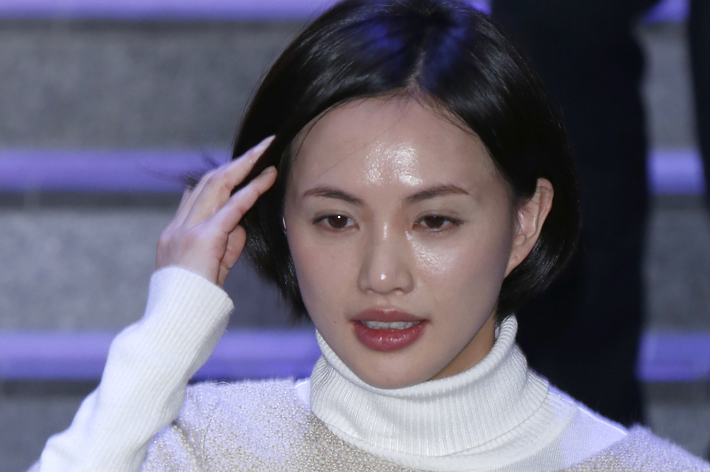 女性が白いタートルネックのドレスを着て階段を歩いている。