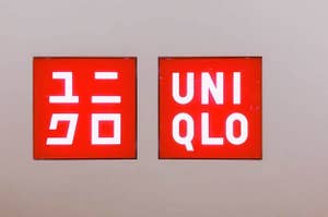 Two signs on a wall with the logos for "UNIQLO," one in Japanese and one in English