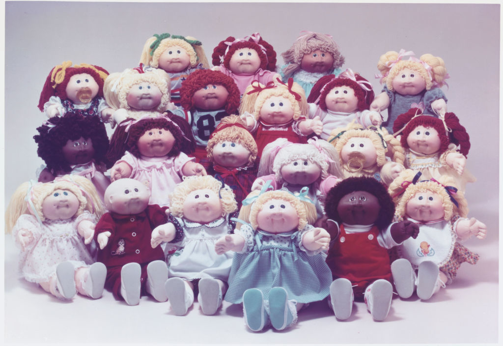 A collection of various Cabbage Patch Kids dolls arranged in rows