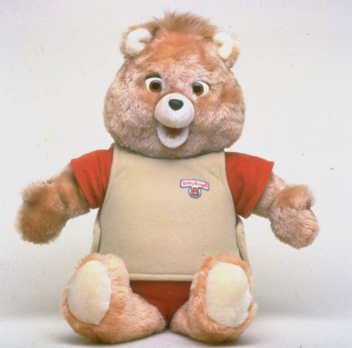 Teddy Ruxpin animatronic toy bear dressed in a casual outfit, seated against a white background