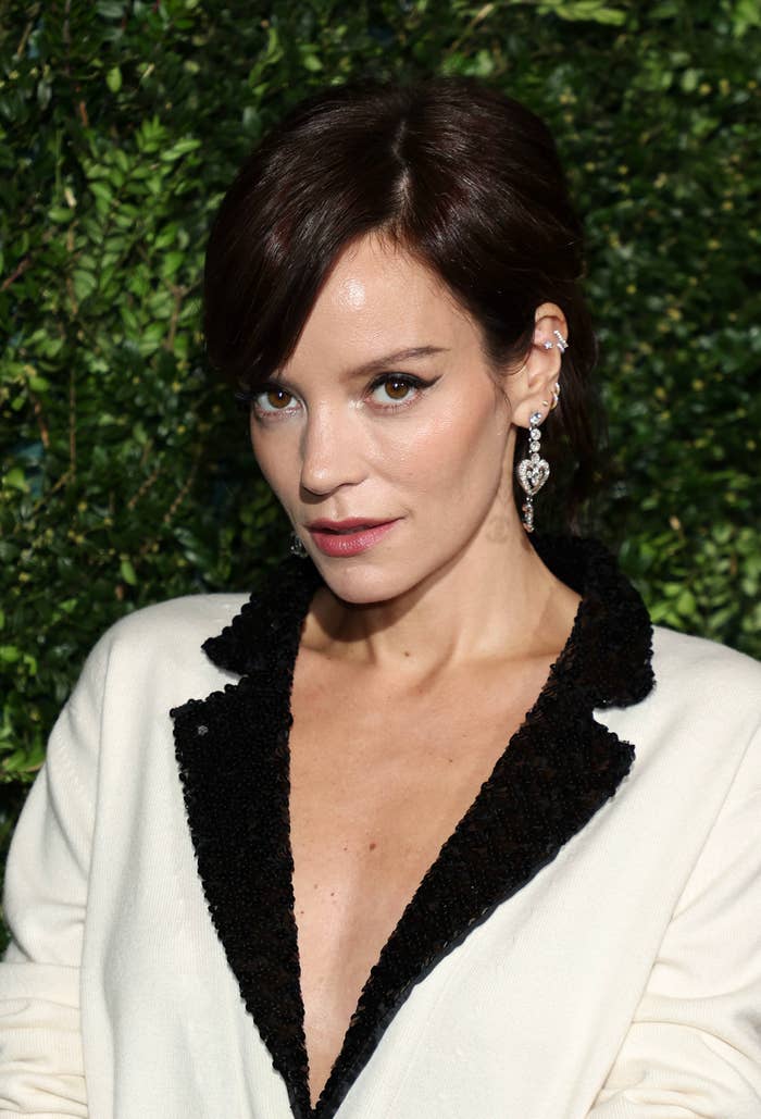 Lily Allen with updo hairstyle, wearing earrings and a v-neck jacket with lapels