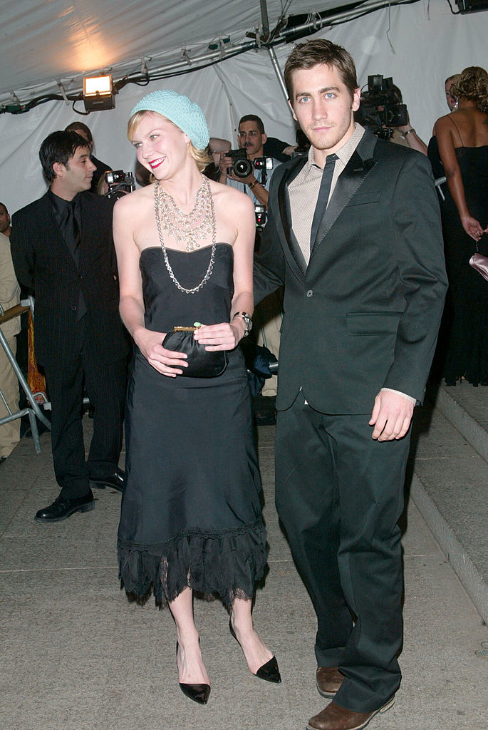 Two celebrities posing; the woman in a beanie and black dress, the man in a suit, at an event
