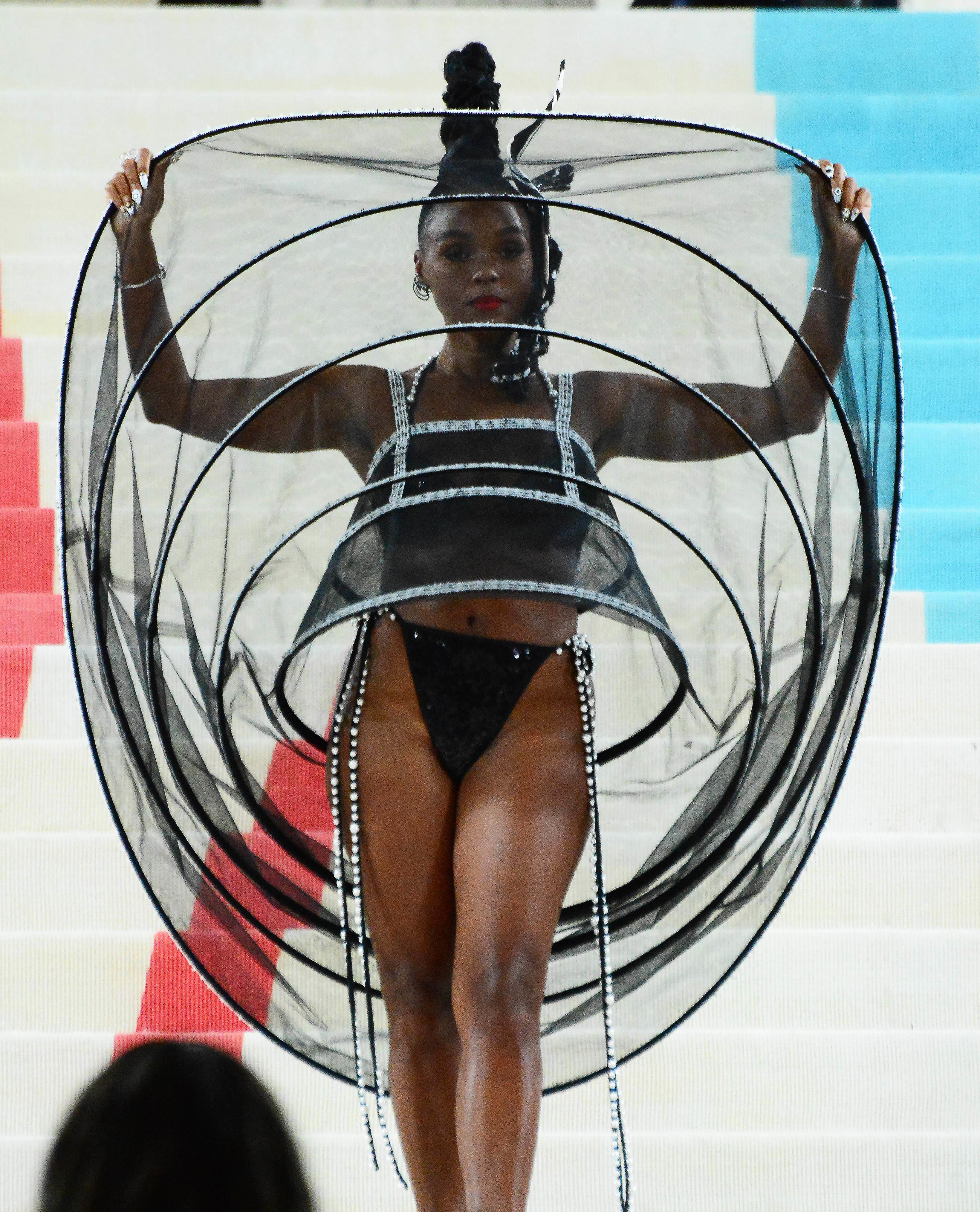 Person in black outfit with a sheer, hoop-embellished cover at an event