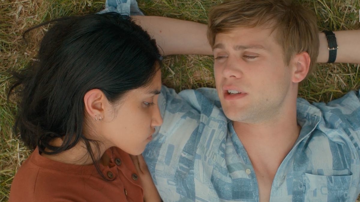 Two characters lie on grass, close-up, appearing in a relaxed or intimate moment