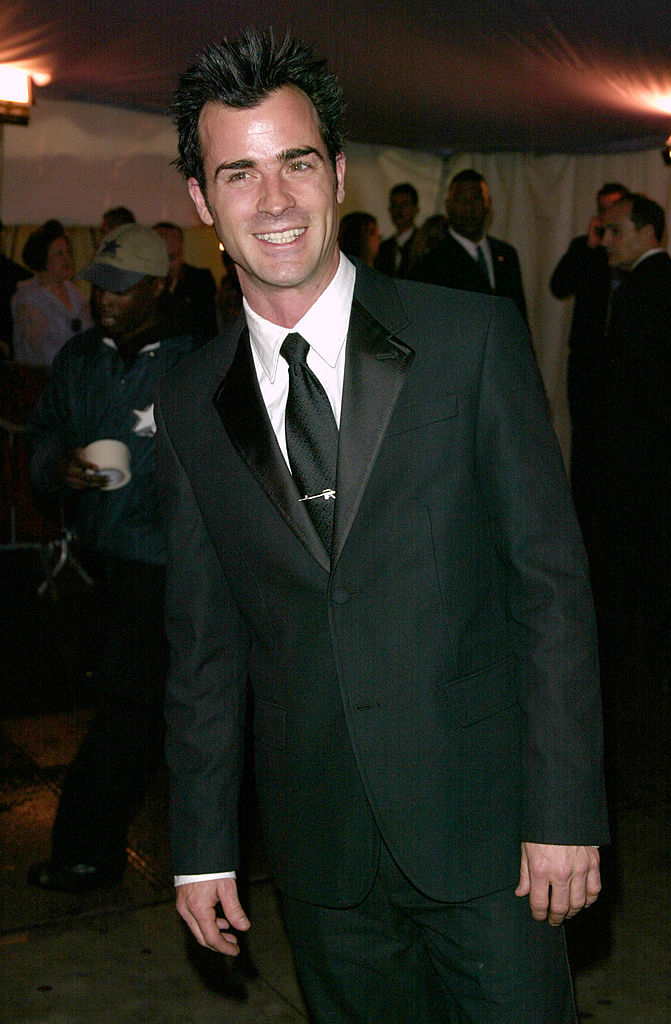 Man in a black suit with a tie, smiling at a celebrity event