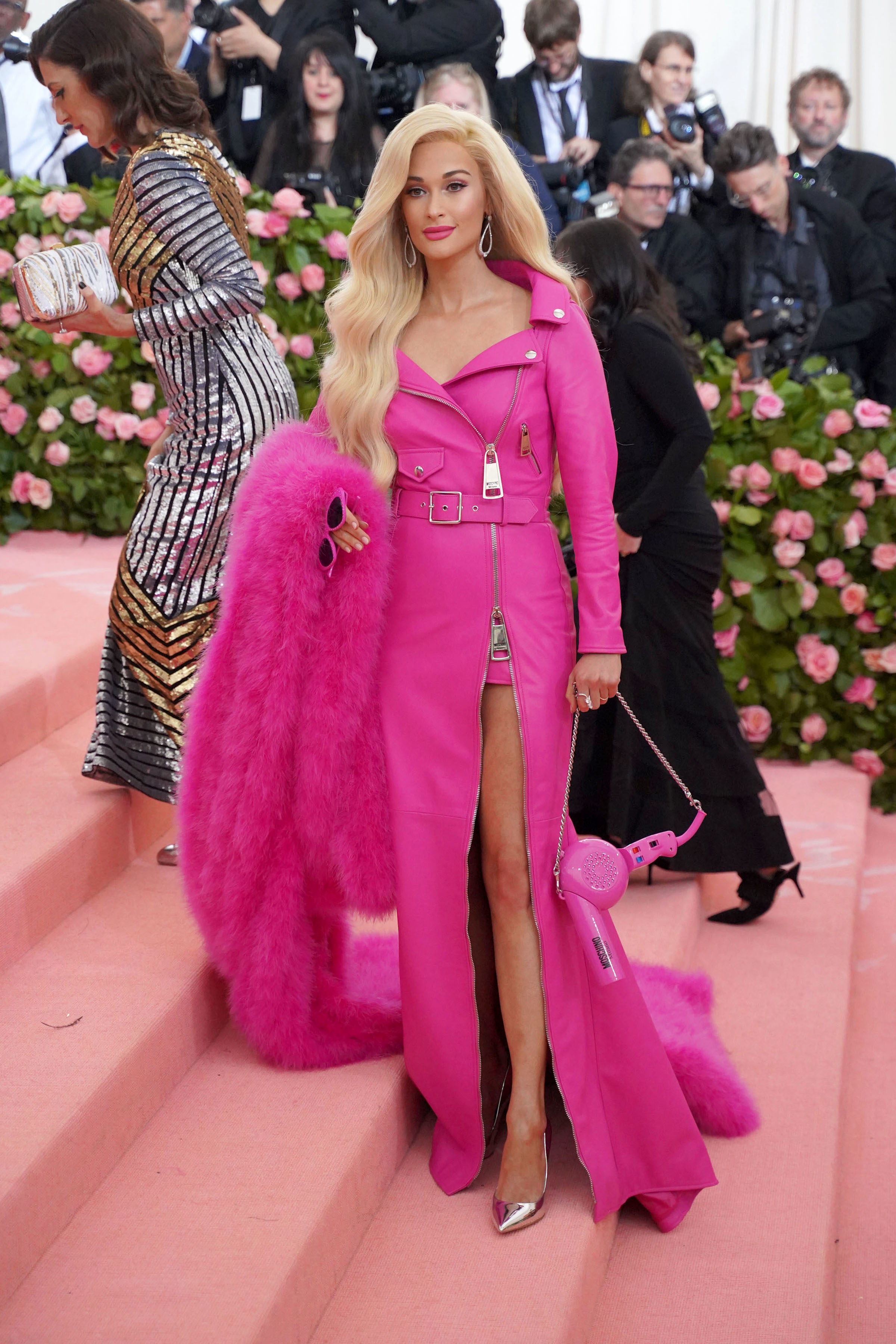 Person in a pink outfit with a high-slit skirt and matching long coat at a gala event