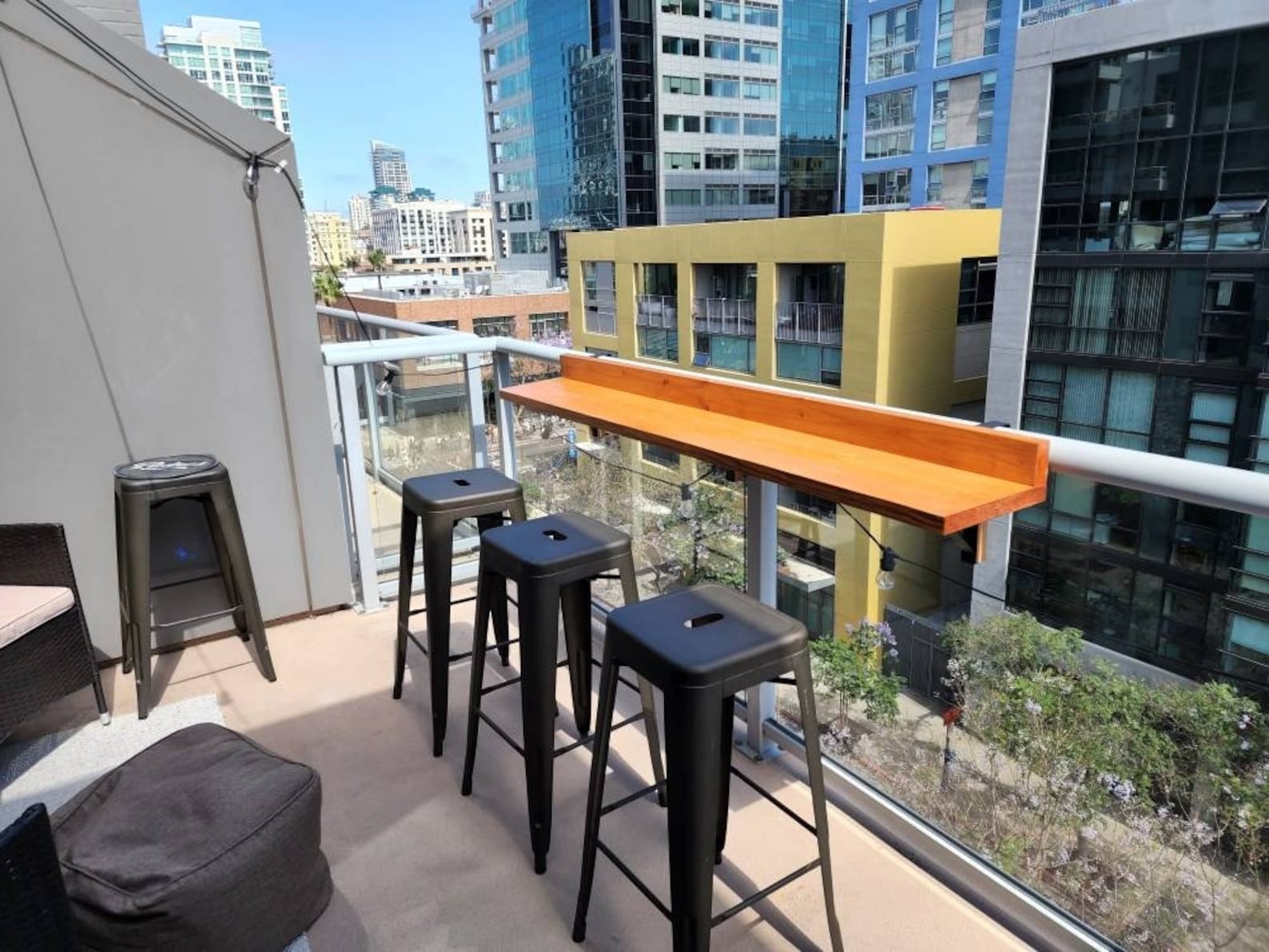 Balcony with a high wooden bar table and stools with urban backdrop, ideal for outdoor shopping inspiration