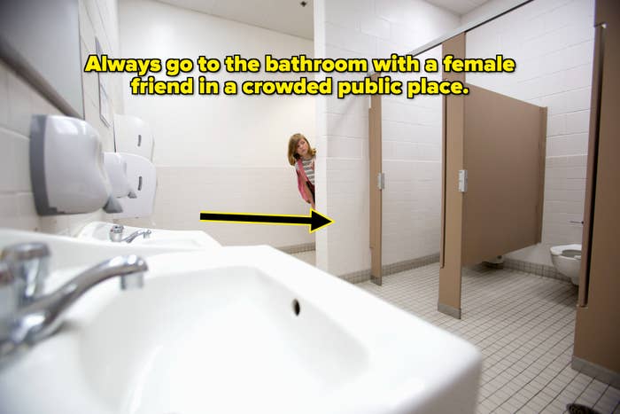 A child peeks out from behind a bathroom stall door next to sinks