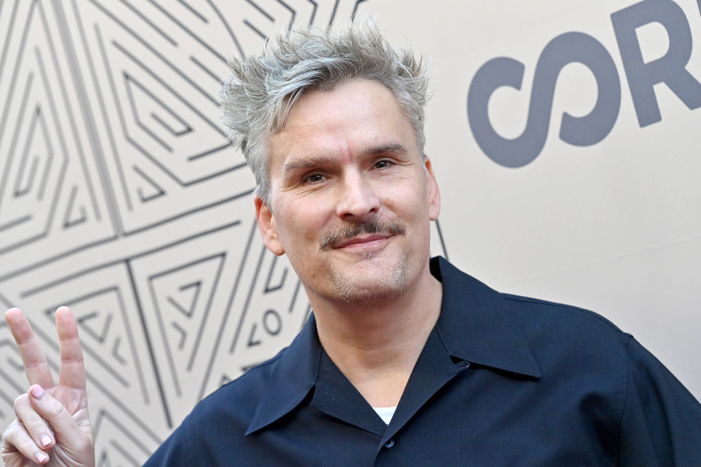 Balthazar Getty in a dark shirt poses with a peace sign on the red carpet
