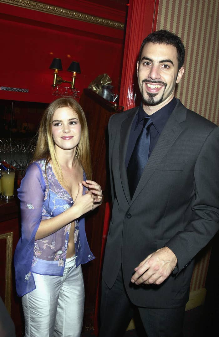 Person in a blue floral top and white pants standing next to a person in a black suit and tie