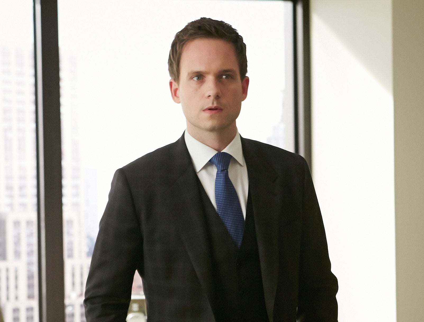 Patrick J. Adams as Mike Ross in &quot;Suits,&quot; wearing a tailored suit and tie, standing in an office setting