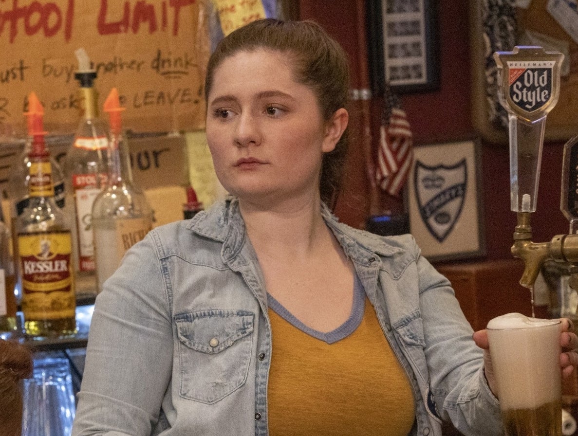 Character Emma Kenney in a denim jacket over a tank top, at a bar with a beer in &quot;Shameless.&quot;