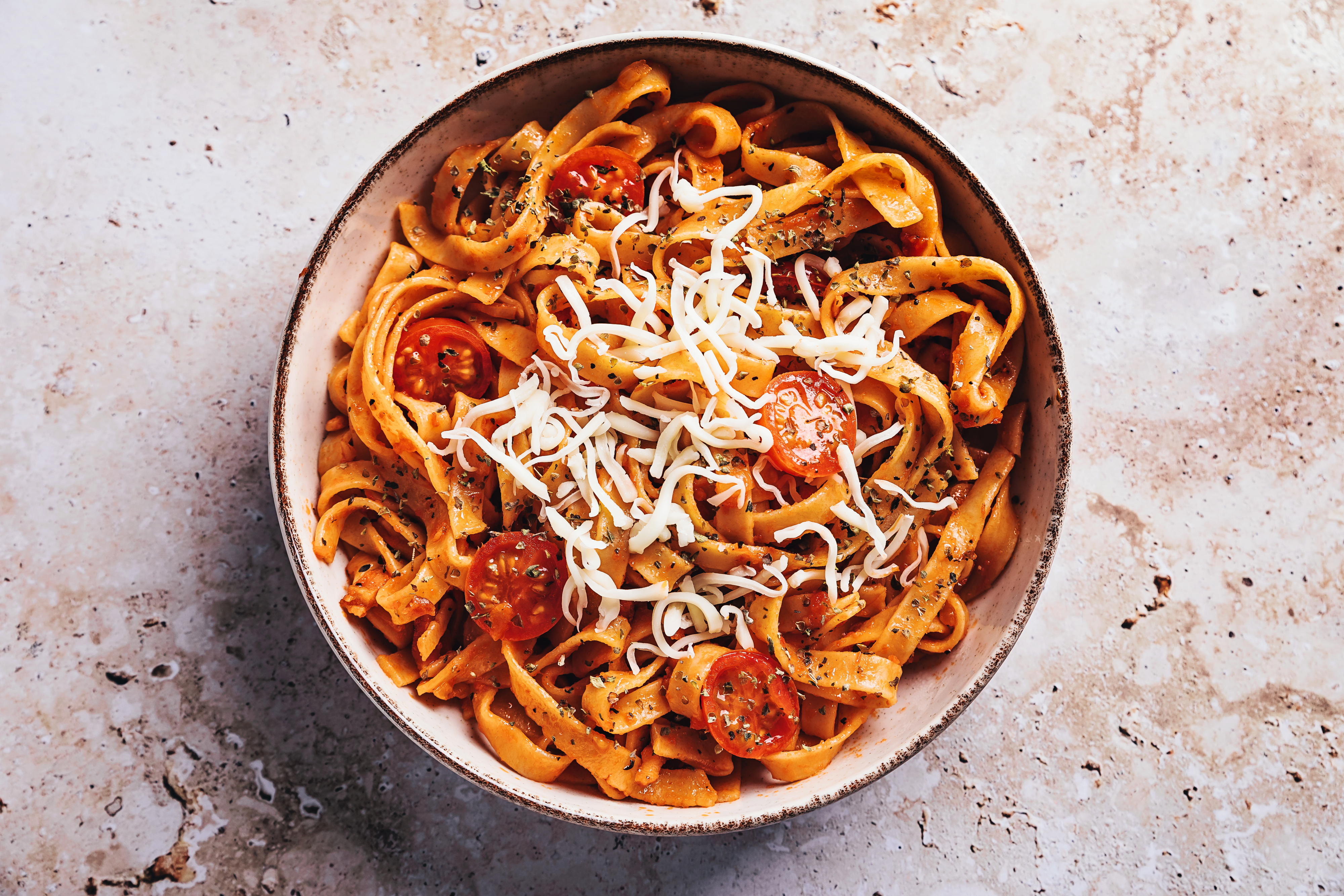 Bowl of pasta with tomatoes and cheese, hinting at a romantic homemade meal