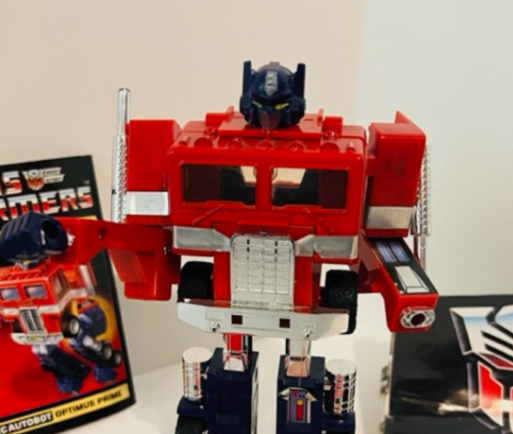 Optimus Prime toy in robot form with Transformers packaging in the background