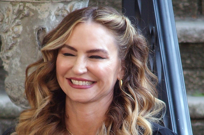 Close-up of a smiling woman with wavy hair, wearing modest earrings