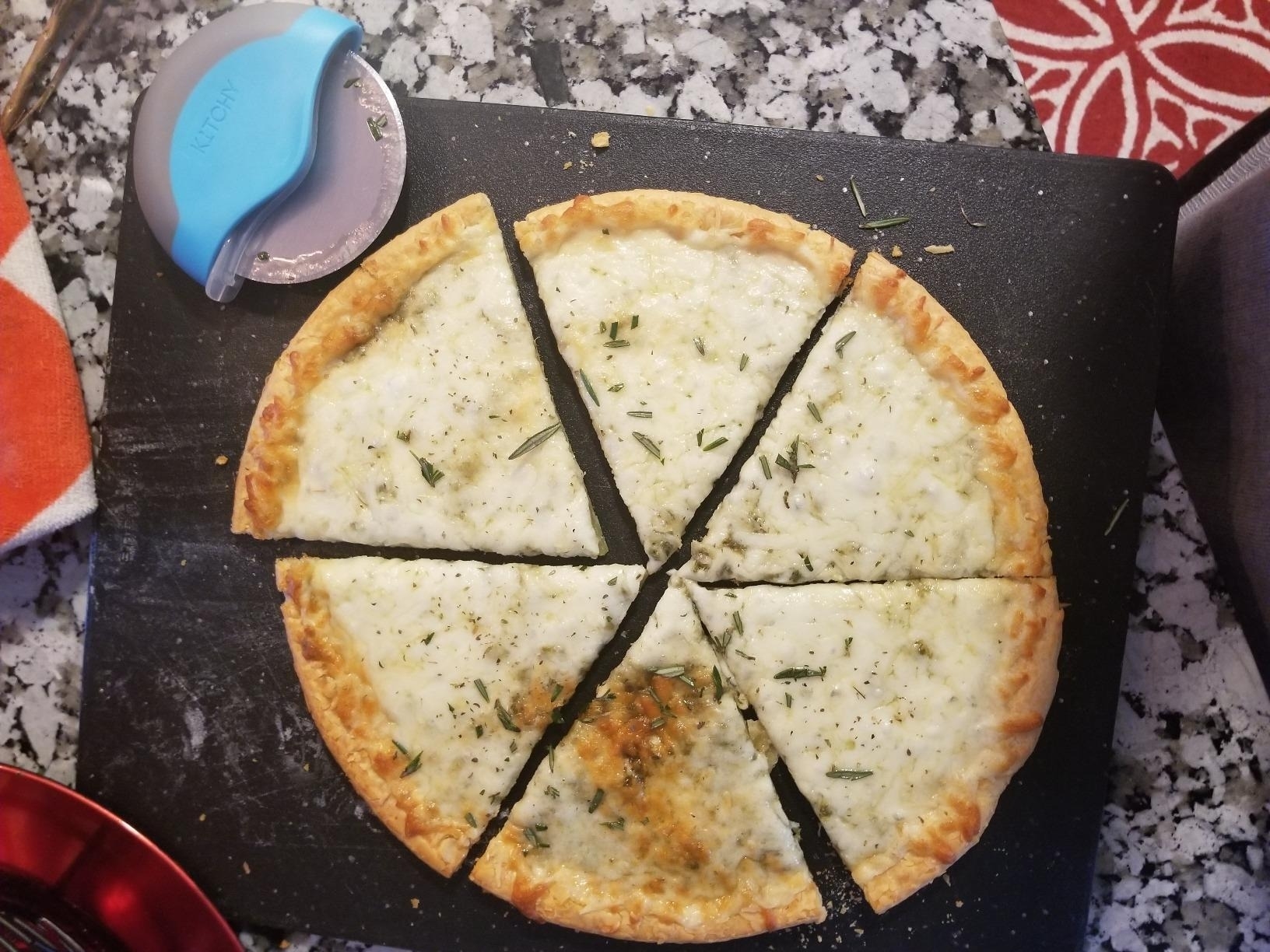 The pizza cutter beside a well-cut pizza