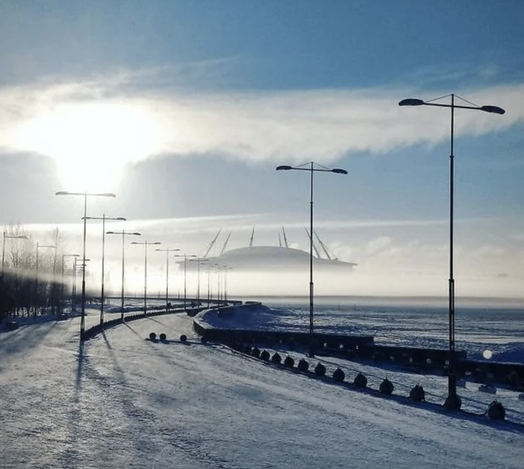 Snow-covered road leading to a bridge with street lamps on the side