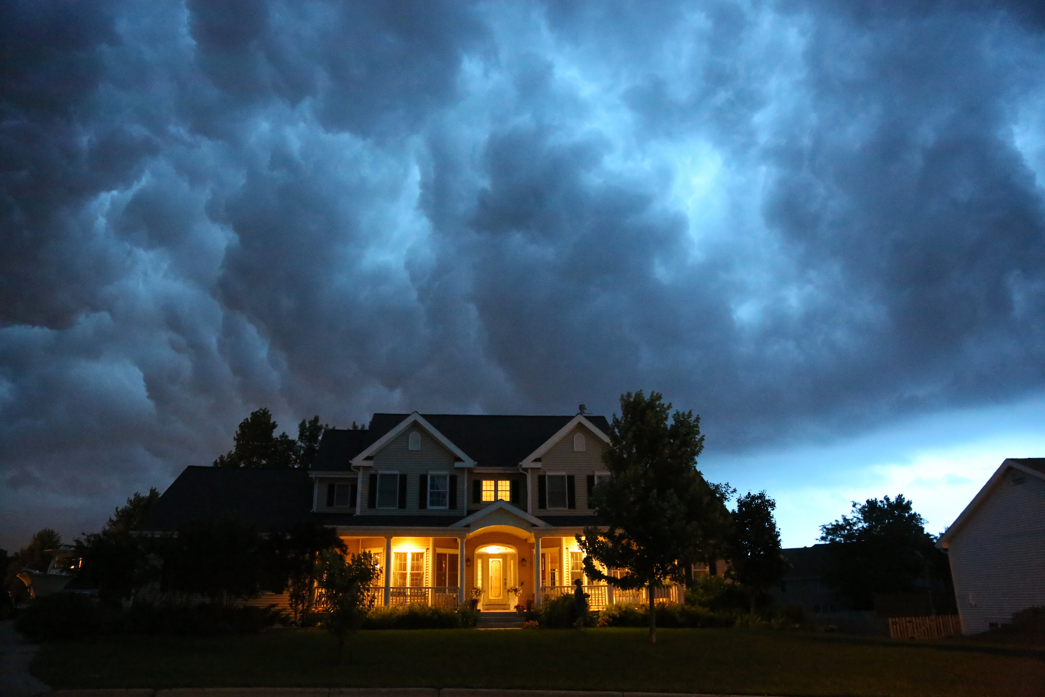Dramatic storm clouds gather above a suburban house at dusk