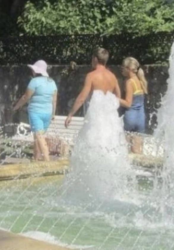 a shirtless man who walked past a fountain so it looked like he was wearing a wedding dress