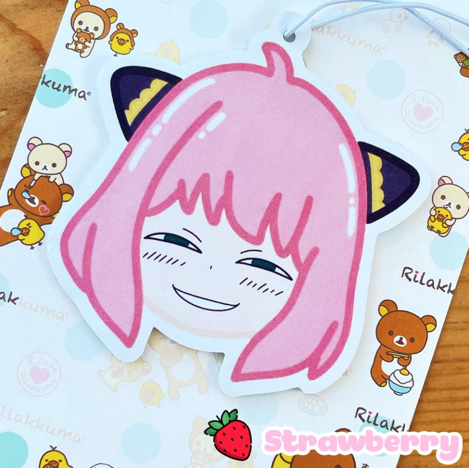 Anya air freshener with a strawberry scent, set against a background with Rilakkuma images