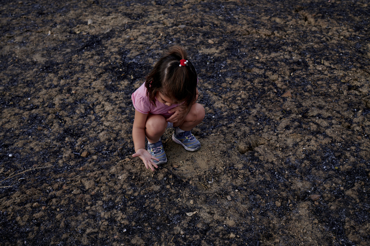 Child crouching on the ground covering their face