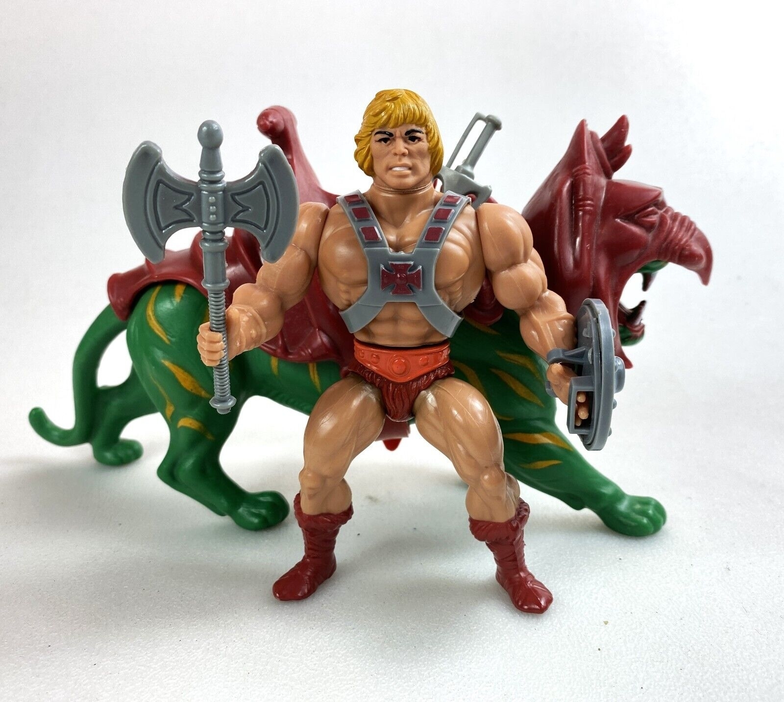 He-Man action figure riding Battle Cat, wielding a sword and an axe, with armor and helmet