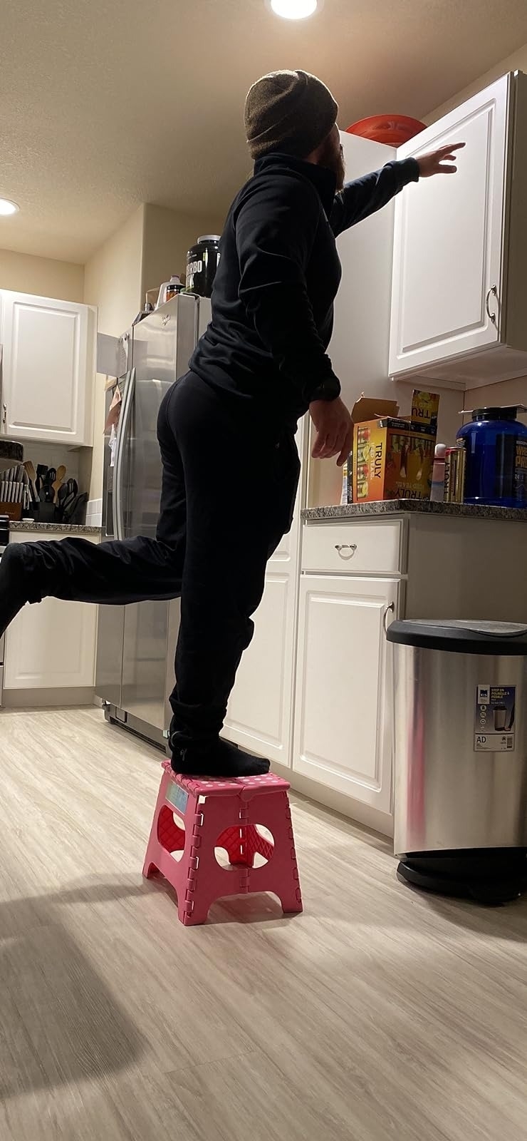 Person using step stool to reach upper kitchen cabinet