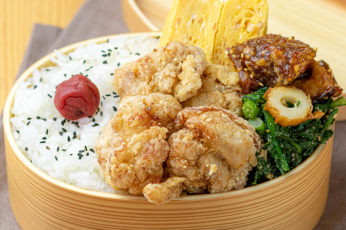 日本の弁当箱に入った唐揚げ、卵焼き、ひじき煮、白米と梅干しです。