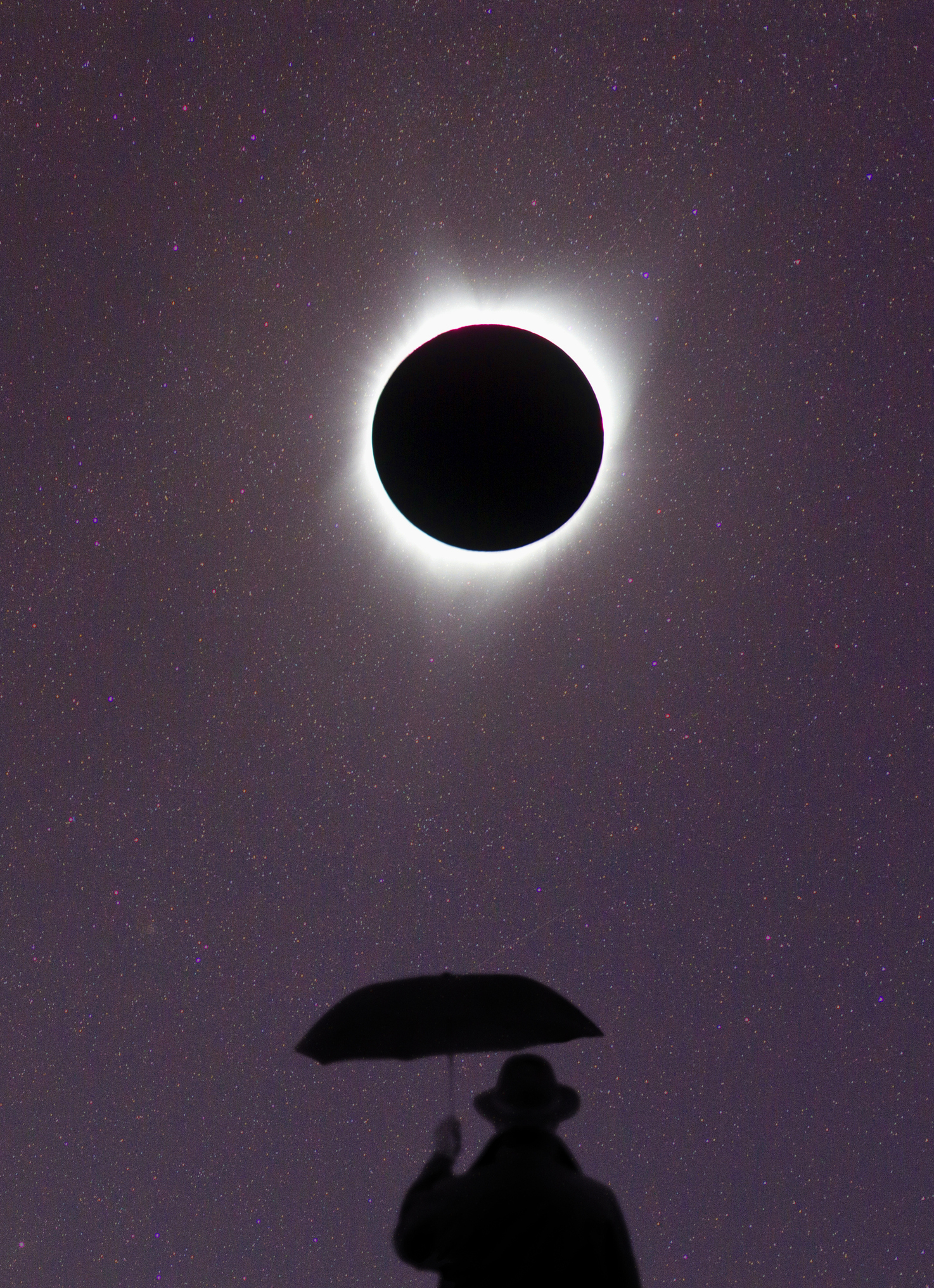 Solar eclipse with a silhouette of a person holding an umbrella underneath
