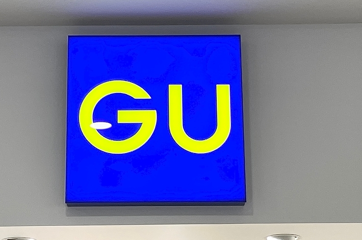 A blue sign with the letters &lsquo;GU&rsquo; mounted on a wall