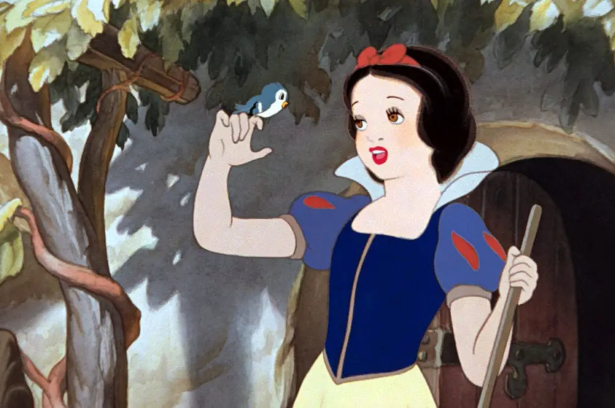 Snow White smiles at a bird on her finger outside a cottage