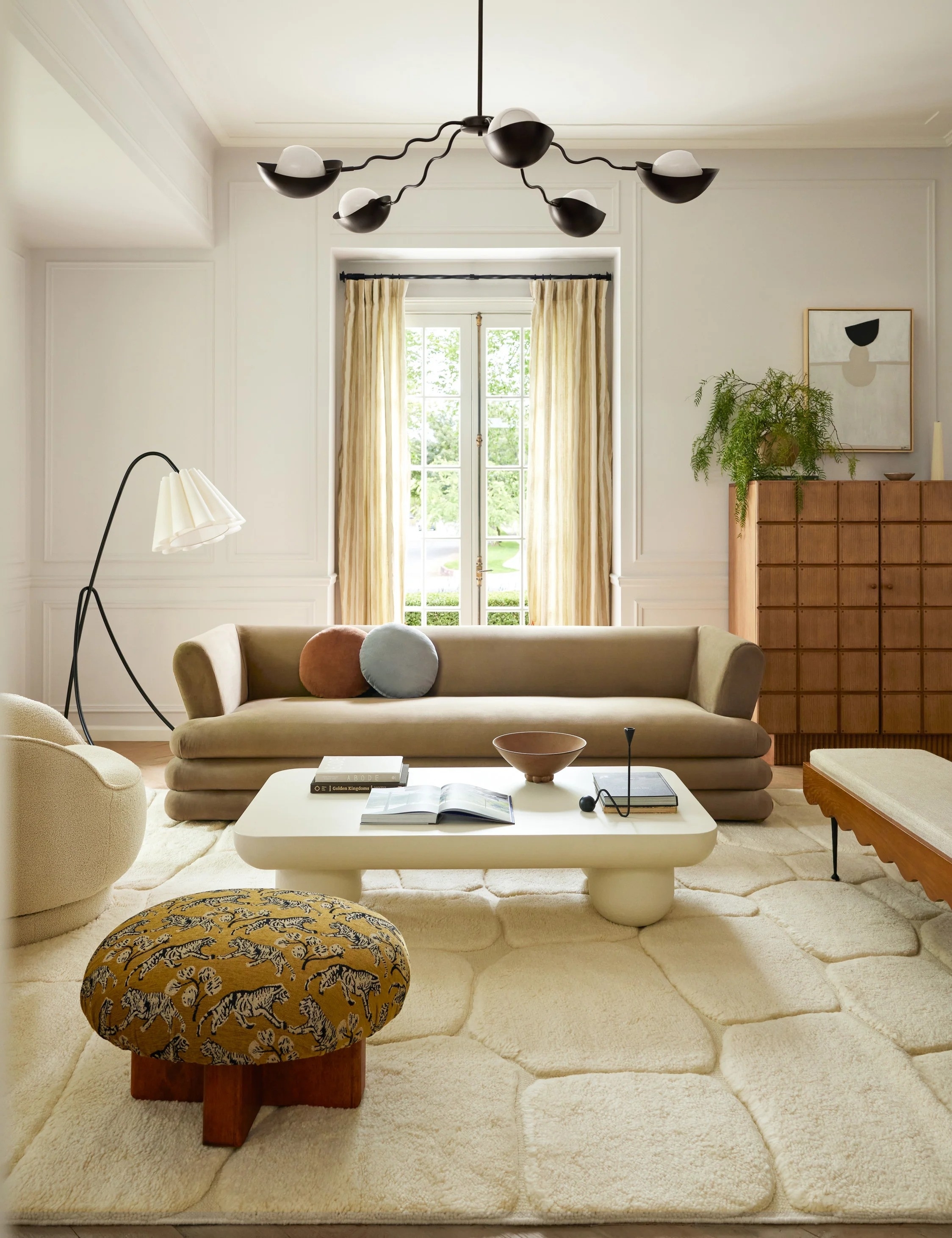 Elegant living room with a mix of modern furniture including a sofa, chairs, and an eclectic stool