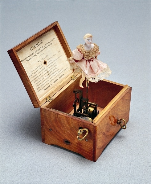 A ballerina figurine on a spring pops out of a wooden music box with a program for &quot;Giselle&quot; inside the lid