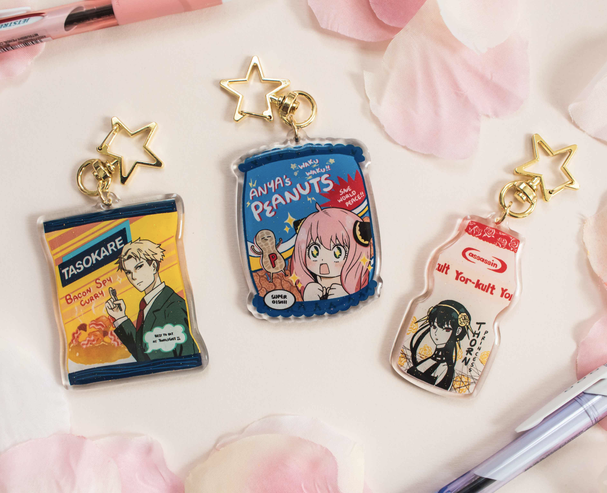 Three anime character crossed with food keychains with decorative elements on a pastel background