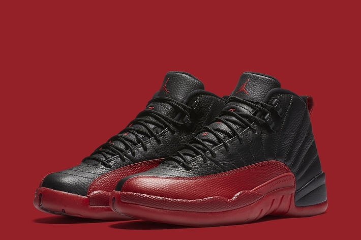 A pair of black and red Air Jordan 13 sneakers against a red background