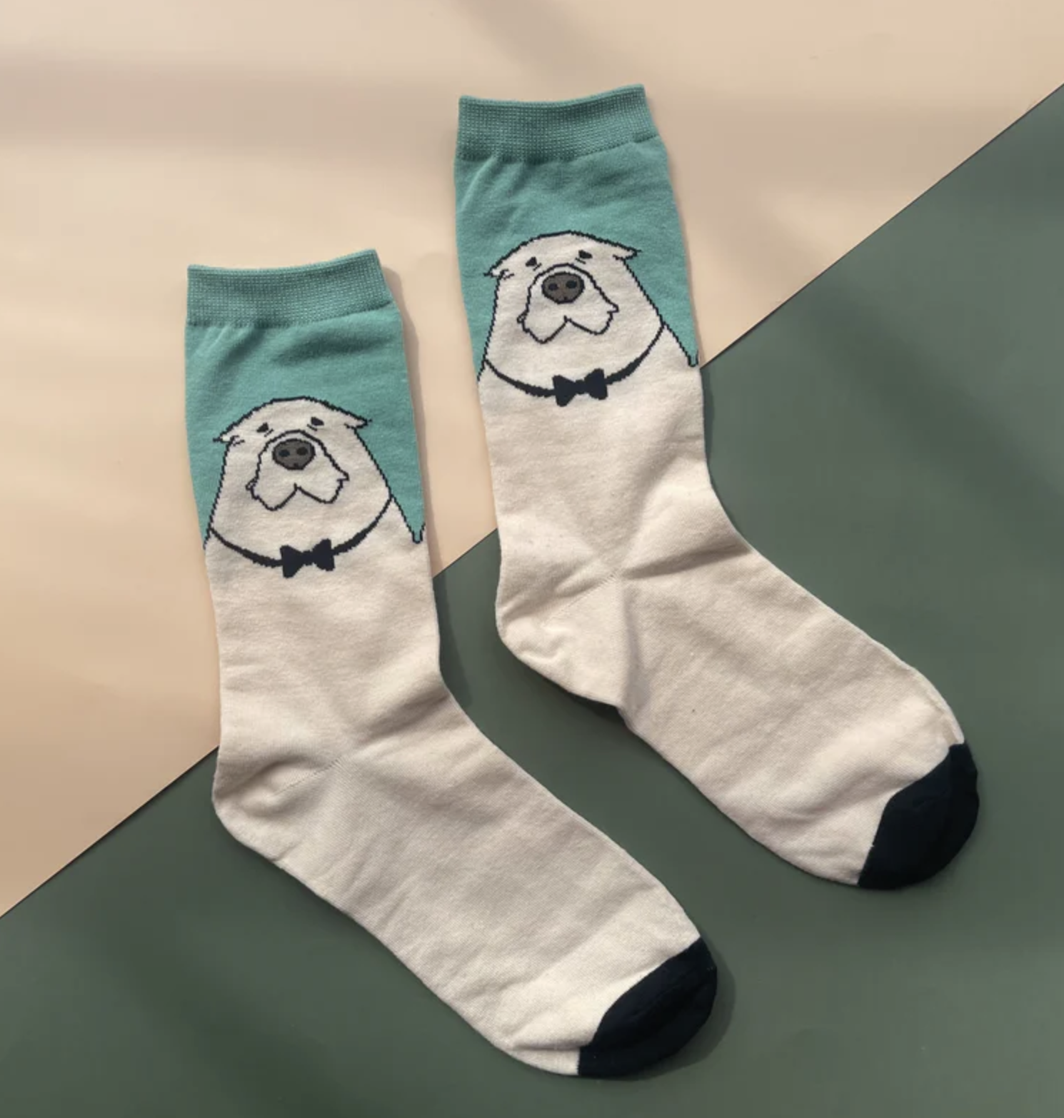 Pair of socks with pug face and bow tie design displayed on a flat surface. Suitable for quirky fashion enthusiasts