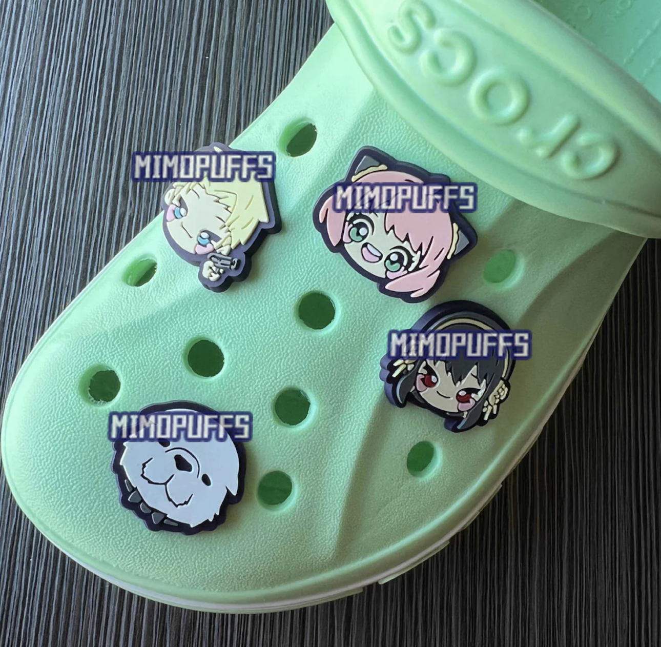 Four animated character shoe charms attached to a single pastel green Croc.