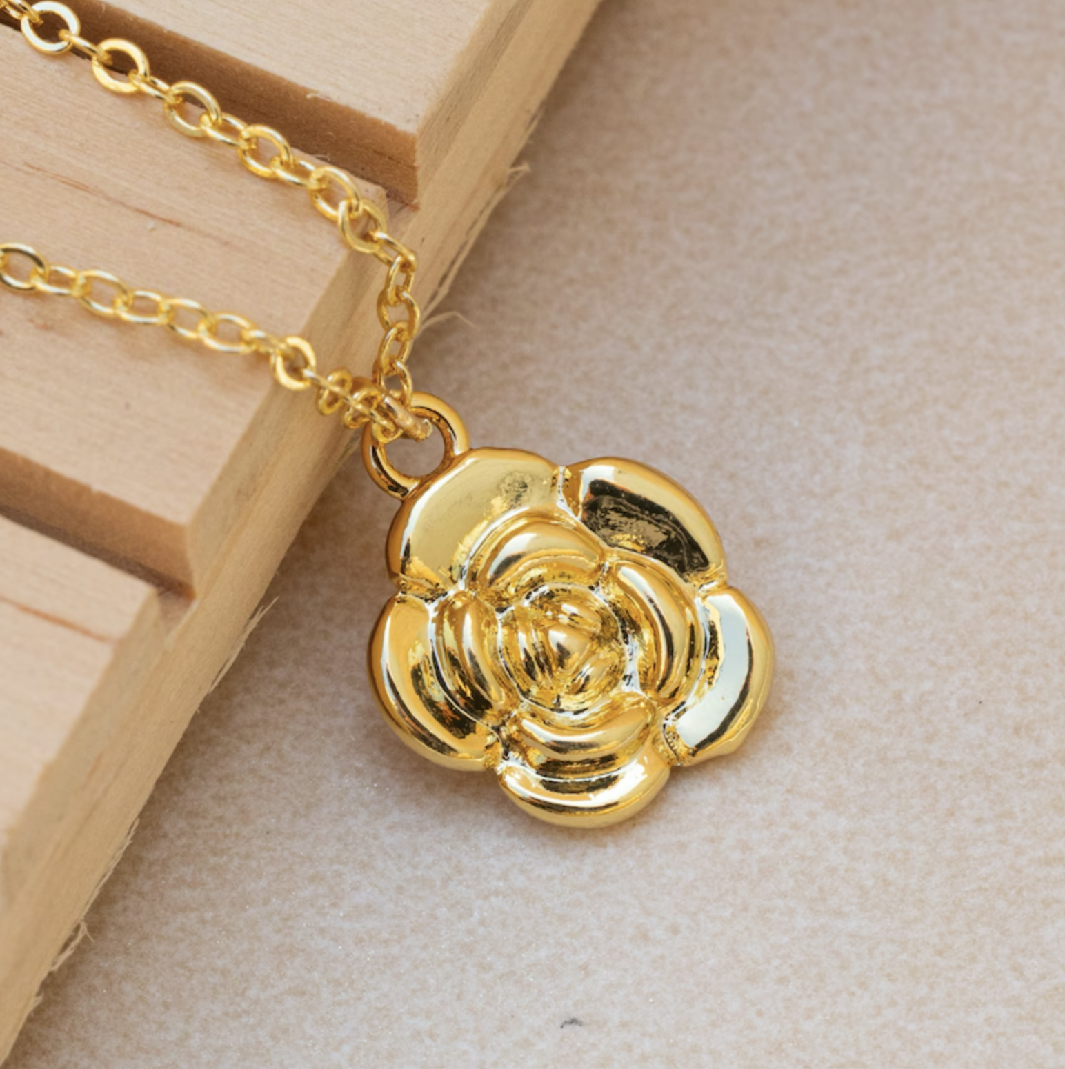 Gold-tone floral pendant on a chain displayed